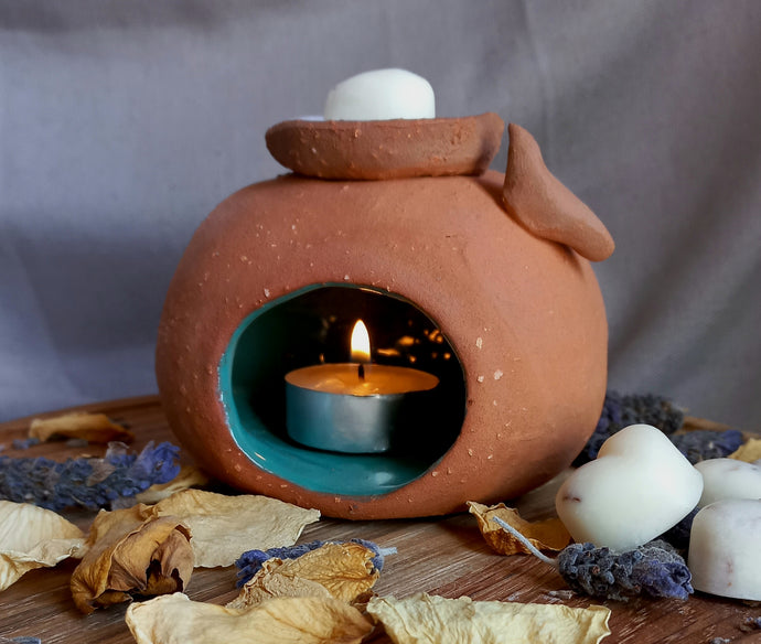 Oil or wax burner in terracotta with green inside. Small clay bird on side and dish for oil or wax to burn